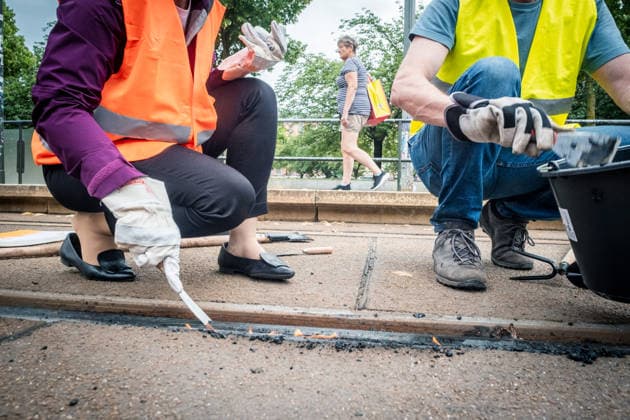 Leipziger Bürgerinnen und Bürger befreien am Johannisplatz gemeinsam mit den Leipziger Verkehrsbetrieben (LVB) die Straßenbahngleise von geschmolzenem Bitumen. Nachdem bereits am Vortag rund 100 Freiwillige einem Aufruf der LVB gefolgt waren, wurden die Reinigungsarbeiten am zweiten Tag am Johannisplatz fortgesetzt. Hintergrund sind die Schäden durch die extremen Temperaturen des vergangenen Hitzewochenendes. Aufnahme vom Datum . Reinigung Leipzig *** Residents of Leipzig are working together with the Leipzig Public Transportation Authority (LVB) to clear melted asphalt from the tram tracks at Johannisplatz. After about 100 volunteers had already responded to a call for help from the LVB the previous day, cleanup efforts continued on t