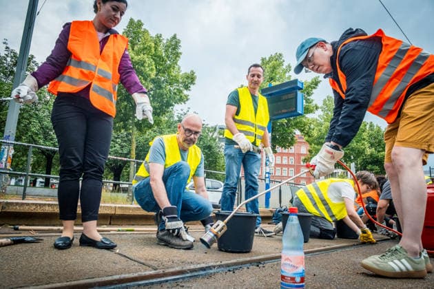 Leipziger Bürgerinnen und Bürger befreien am Johannisplatz gemeinsam mit den Leipziger Verkehrsbetrieben (LVB) die Straßenbahngleise von geschmolzenem Bitumen. Nachdem bereits am Vortag rund 100 Freiwillige einem Aufruf der LVB gefolgt waren, wurden die Reinigungsarbeiten am zweiten Tag am Johannisplatz fortgesetzt. Hintergrund sind die Schäden durch die extremen Temperaturen des vergangenen Hitzewochenendes. Aufnahme vom Datum . Reinigung Leipzig *** Residents of Leipzig are working together with the Leipzig Public Transportation Authority (LVB) to clear melted asphalt from the tram tracks at Johannisplatz. After about 100 volunteers had already responded to a call for help from the LVB the previous day, cleanup efforts continued on t