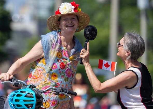 (260701) -- TORONTO, July 1, 2026 -- People cool off with a portable fan during the 2026 Canada Day Parade in Toronto, Canada, July 1, 2026. (Photo by Zou Zheng Xinhua) CANADA-TORONTO-CANADA DAY-PARADE LinxWei 
