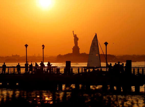 People gather on a dock as the sun sets behind the Statue of Liberty in the days leading up to the July 4th holiday and the 250th anniversary of the United States on Wednesday, July 1, 2026 in New York City.  NYP20260701169 JOHNxANGELILLO
