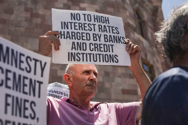 ARMENIA, YEREVAN - JULY 2, 2026: Protesters are seen outside the Government House amid talks between European Commission President von der Leyen and Armenia s President Pashinyan. The message on the sign reads: No to high interest rates charged by banks and credit institutions . Alexander Patrin TASS  94570244