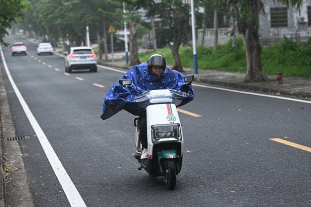 (260703) -- QIONGHAI, July 3, 2026 -- A citizen rides an electric bicycle amid wind and rain in Qionghai, south China s Hainan Province, July 3, 2026. Typhoon Maysak, the 10th typhoon of the year, made landfall on the coast of south China s Hainan Province on Friday evening, suspending train, ferry and flight services and closing schools in some areas. The tropical storm came ashore at around 6:20 p.m. in Yelin Township of Lingshui Li Autonomous County, according to the Hainan provincial meteorological bureau. At landfall, it packed maximum winds of 23 meters per second near its center. The typhoon is forecast to move northwest, passing through Baoting, Wuzhishan, Baisha and Danzhou before entering the Beibu Gulf, the meteorological 