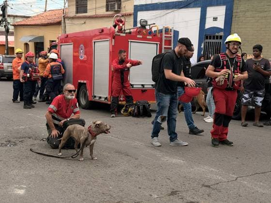 One person injured after partial collapse of school building in La Pastora, Venezuela CARACAS, VENEZUELA - JULY 3: A rescue worker kneels on the street next to a search dog with a brindled coat in La Pastora, Caracas, Venezuela, on July 3, 2026. In the background, a red fire truck bearing the Civil Protection logo is visible, along with several uniformed personnel coordinating the response efforts alongside local residents. Part of the Agustiniano San Judas Tadeo School building, collapsed on the afternoon of Friday, nine days after the country was struck by a double earthquake. Although the building had been evacuated due to severe damage, one person was injured. Julio Urribarri Anadolu Caracas Venezuela. Editorial use only. Please get i  Copyright: x2026xAnadoluxJulioxUrribarrix