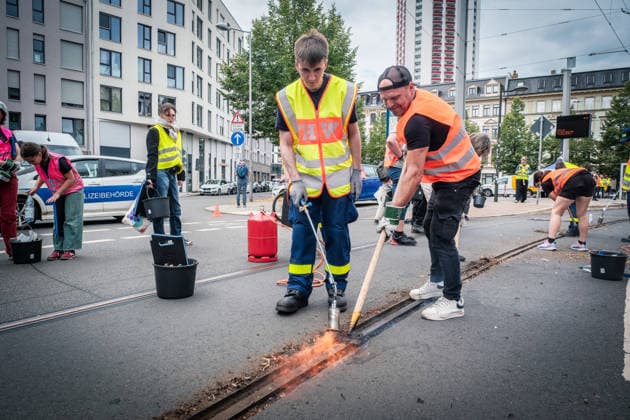 Freiwillige Helfer reinigen gemeinsam mit Mitarbeitenden der Leipziger Verkehrsbetriebe (LVB) Straßenbahngleise an der Leibnizstraße in Leipzig (Sachsen) von geschmolzenem Bitumen. Die Arbeiten sind Teil eines dritten Subbotniks zur Beseitigung der Hitzeschäden am Straßenbahnnetz. Aufnahme vom 4. Juli 2026. Hilfsaktion Leipzig *** Volunteers are working alongside employees of the Leipzig Public Transportation Authority (LVB) to clean melted bitumen from the tram tracks on Leibnizstraße in Leipzig, Saxony. The work is part of a third subbotnik aimed at repairing heat damage to the tram network. Photo taken on July 4, 2026. VolunteerLeipzig Relief Effort