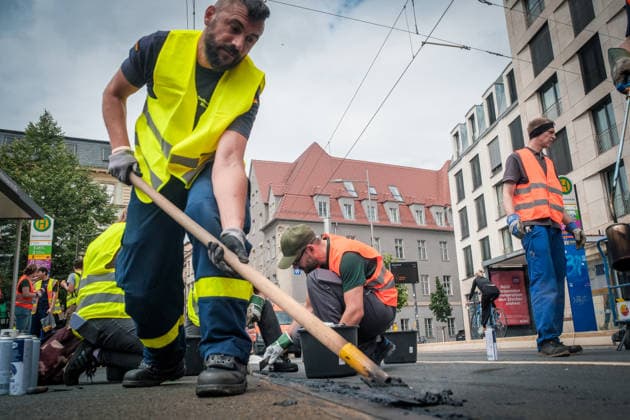 Freiwillige Helfer reinigen gemeinsam mit Mitarbeitenden der Leipziger Verkehrsbetriebe (LVB) Straßenbahngleise an der Leibnizstraße in Leipzig (Sachsen) von geschmolzenem Bitumen. Die Arbeiten sind Teil eines dritten Subbotniks zur Beseitigung der Hitzeschäden am Straßenbahnnetz. Aufnahme vom 4. Juli 2026. Hilfsaktion Leipzig *** Volunteers are working alongside employees of the Leipzig Public Transportation Authority (LVB) to clean melted bitumen from the tram tracks on Leibnizstraße in Leipzig, Saxony. The work is part of a third subbotnik aimed at repairing heat damage to the tram network. Photo taken on July 4, 2026. VolunteerLeipzig Relief Effort