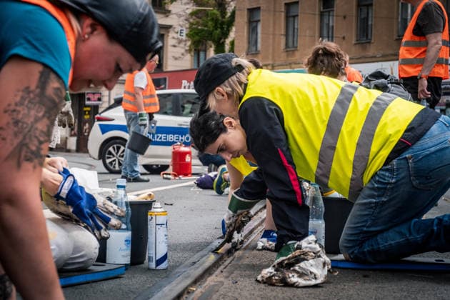 Freiwillige Helfer reinigen gemeinsam mit Mitarbeitenden der Leipziger Verkehrsbetriebe (LVB) Straßenbahngleise an der Leibnizstraße in Leipzig (Sachsen) von geschmolzenem Bitumen. Die Arbeiten sind Teil eines dritten Subbotniks zur Beseitigung der Hitzeschäden am Straßenbahnnetz. Aufnahme vom 4. Juli 2026. Hilfsaktion Leipzig *** Volunteers are working alongside employees of the Leipzig Public Transportation Authority (LVB) to clean melted bitumen from the tram tracks on Leibnizstraße in Leipzig, Saxony. The work is part of a third subbotnik aimed at repairing heat damage to the tram network. Photo taken on July 4, 2026. VolunteerLeipzig Relief Effort