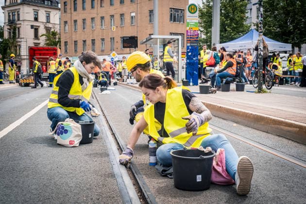 Freiwillige Helfer reinigen gemeinsam mit Mitarbeitenden der Leipziger Verkehrsbetriebe (LVB) Straßenbahngleise an der Leibnizstraße in Leipzig (Sachsen) von geschmolzenem Bitumen. Die Arbeiten sind Teil eines dritten Subbotniks zur Beseitigung der Hitzeschäden am Straßenbahnnetz. Aufnahme vom 4. Juli 2026. Hilfsaktion Leipzig *** Volunteers are working alongside employees of the Leipzig Public Transportation Authority (LVB) to clean melted bitumen from the tram tracks on Leibnizstraße in Leipzig, Saxony. The work is part of a third subbotnik aimed at repairing heat damage to the tram network. Photo taken on July 4, 2026. VolunteerLeipzig Relief Effort
