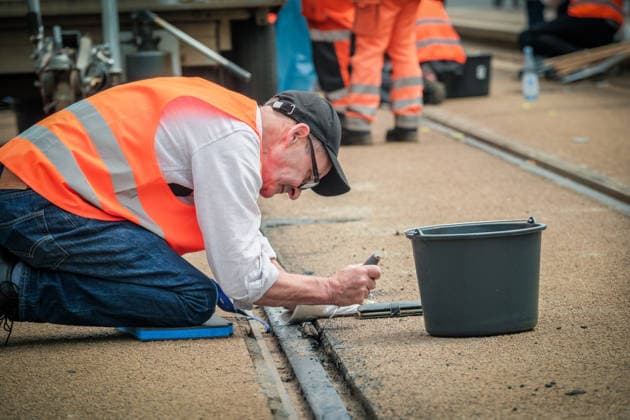 Freiwillige Helfer reinigen gemeinsam mit Mitarbeitenden der Leipziger Verkehrsbetriebe (LVB) Straßenbahngleise an der Leibnizstraße in Leipzig (Sachsen) von geschmolzenem Bitumen. Die Arbeiten sind Teil eines dritten Subbotniks zur Beseitigung der Hitzeschäden am Straßenbahnnetz. Aufnahme vom 4. Juli 2026. Hilfsaktion Leipzig *** Volunteers are working alongside employees of the Leipzig Public Transportation Authority (LVB) to clean melted bitumen off the tram tracks on Leibnizstraße in Leipzig, Saxony. The work is part of a third subbotnik aimed at repairing heat damage to the tram network. Photo taken on July 4, 2026. VolunteerLeipzig Relief Effort