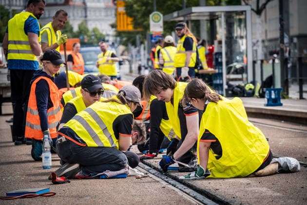 Freiwillige Helfer reinigen gemeinsam mit Mitarbeitenden der Leipziger Verkehrsbetriebe (LVB) Straßenbahngleise an der Leibnizstraße in Leipzig (Sachsen) von geschmolzenem Bitumen. Die Arbeiten sind Teil eines dritten Subbotniks zur Beseitigung der Hitzeschäden am Straßenbahnnetz. Aufnahme vom 4. Juli 2026. Hilfsaktion Leipzig *** Volunteers are working alongside employees of the Leipzig Public Transportation Authority (LVB) to clean melted bitumen from the tram tracks on Leibnizstraße in Leipzig, Saxony. The work is part of a third subbotnik aimed at repairing heat damage to the tram network. Photo taken on July 4, 2026. VolunteerLeipzig Relief Effort