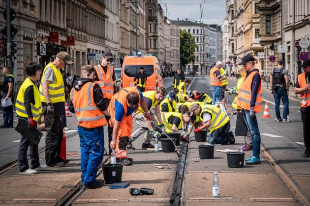 Freiwillige Helfer reinigen gemeinsam mit Mitarbeitenden der Leipziger Verkehrsbetriebe (LVB) Straßenbahngleise an der Leibnizstraße in Leipzig (Sachsen) von geschmolzenem Bitumen. Die Arbeiten sind Teil eines dritten Subbotniks zur Beseitigung der Hitzeschäden am Straßenbahnnetz. Aufnahme vom 4. Juli 2026. Hilfsaktion Leipzig *** Volunteers are working alongside employees of the Leipzig Public Transportation Authority (LVB) to clean melted bitumen from the tram tracks on Leibnizstraße in Leipzig, Saxony. The work is part of a third subbotnik aimed at repairing heat damage to the tram network. Photo taken on July 4, 2026. VolunteerLeipzig Relief Effort