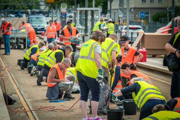 Freiwillige Helfer reinigen gemeinsam mit Mitarbeitenden der Leipziger Verkehrsbetriebe (LVB) Straßenbahngleise an der Leibnizstraße in Leipzig (Sachsen) von geschmolzenem Bitumen. Die Arbeiten sind Teil eines dritten Subbotniks zur Beseitigung der Hitzeschäden am Straßenbahnnetz. Aufnahme vom 4. Juli 2026. Hilfsaktion Leipzig *** Volunteers are working alongside employees of the Leipzig Public Transportation Authority (LVB) to clean melted bitumen from the tram tracks on Leibnizstraße in Leipzig, Saxony. The work is part of a third subbotnik aimed at repairing heat damage to the tram network. Photo taken on July 4, 2026. VolunteerLeipzig Relief Effort