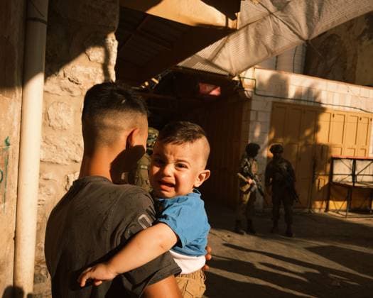 A child is seen crying in front of Israeli occupation forces as they secure provocative tours by Israeli settlers in Hebron™s Old City. HEBRON, WEST BANK JULY 2026: A young child cries while being carried in his older brother s arms in Hebron s Old City as Israeli forces are deployed during an organized visit by Israeli settlers to the area. Hebron s Old City frequently experiences heightened security measures during such visits, which are often accompanied by tensions between settlers and Palestinian residents. Hebron Palestine, State of Copyright: x xBayanxmasalmahx xJNAxPressx