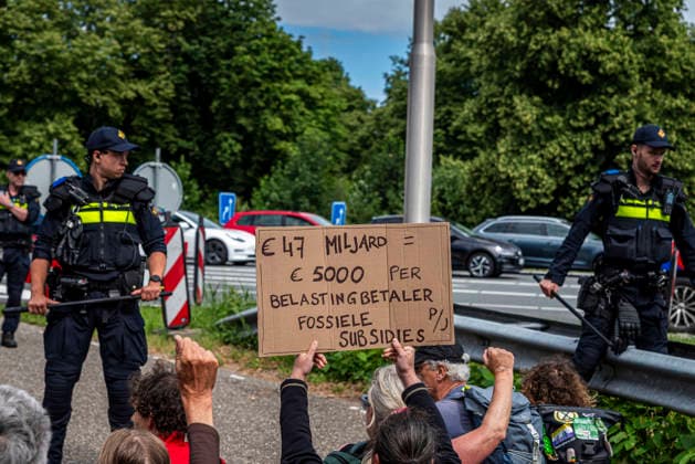 July 4, 2026, Utrecht, Utrecht, Netherlands: 4 July 2026, Utrecht, the Netherlands. A climate activist holds a sign reading Ã¢öÂ¬47 Billion = Ã¢öÂ¬5000 per taxpayer per year for fossil subsidies (translated from Dutch). Climate activists from Extinction Rebellion and Utrecht for Palestine block the A12 highway near Utrecht, Netherlands, demanding an end to billions in annual fossil fuel subsidies. Utrecht Netherlands  - ZUMAp202 20260704_zip_p202_018 Copyright: xJamesxPetermeierx