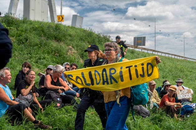 July 4, 2026, Utrecht, Utrecht, Netherlands: 4 July 2026, Utrecht, the Netherlands. A climate activist, while being arrested, holds a banner reading Solidarity (translated from Dutch). Climate activists from Extinction Rebellion and Utrecht for Palestine block the A12 highway near Utrecht, Netherlands, demanding an end to billions in annual fossil fuel subsidies. Utrecht Netherlands - ZUMAp202 20260704_zip_p202_015 Copyright: xJamesxPetermeierx