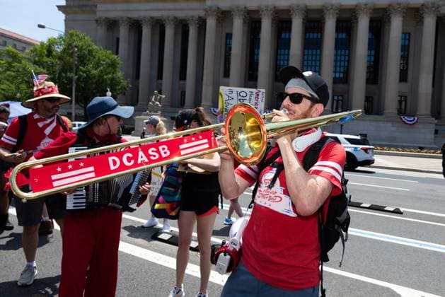 March against Trump on Independence Day in Washington, DC WASHINGTON D.C., USA JULY 4, 2026: A member of the DC Activist Street Band play trombone during We The People 250, a march against abuse of power by U.S. President Donald Trump and his administration. The march ended early due to record heat in the nation™s capital. WASHINGTON, D.C. DC United States of America Copyright: x xAllisonxBaileyx xJNAxPressx