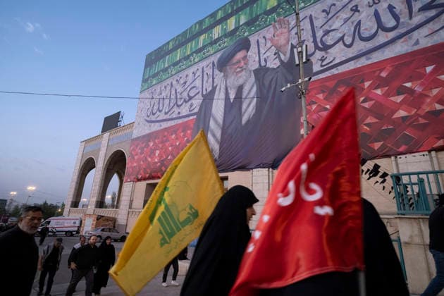 Farewell Ceremony For Bodies Of Supreme Leader And His Family A veiled Iranian mourner carrying a Hezbollah flag walks beneath a giant portrait of Iran s late Supreme Leader Ayatollah Ali Khamenei as she arrives at the Imam Khomeini Grand Mosque to participate in a farewell ceremony for the bodies of Iran s Supreme Leader and his family on the eve of his funeral in Tehran, Iran, on July 4, 2026. Tehran Tehran Iran  Copyright: xMortezaxNikoubazlx originalFilename: nikoubazl-farewell260704_npMKS.jpg