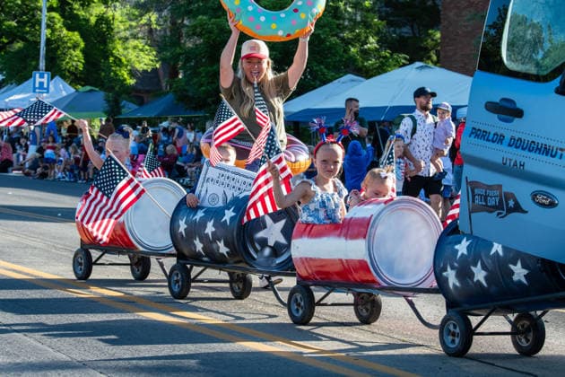 July 4, 2026, Provo, Utah, USA: Children ride in a barrel train decorated with a patriotic stars and stripes theme as a woman holds an inflatable donut beside a Parlor Doughnuts vehicle during America s Freedom Festival Grand Parade in Provo, Utah, Saturday, July 4, 2026. The annual Independence Day event features expanded programming to honor the 250th anniversary of United States independence. Provo USA - ZUMAm292 20260704_znp_m292_131 Copyright: xCharlesxMcClintockxWilsonx