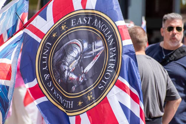 July 4, 2026, Dover, United Kingdom: A far-right activist holds a Union Jack with a far-right coat of arm before a protest march in Dover. Around 100-120 supporters of the Pink Ladies gathered from across the country in Dover, UK. The Pink Ladies is an anti immigration far-right movement. The far-right activists marched through central Dover to the Immigration Centre and they were confronted by a small group of antifascist counter-protesters during their march. Dover United Kingdom  - ZUMAs197 20260704_aaa_s197_218 Copyright: xKrisztianxElekx