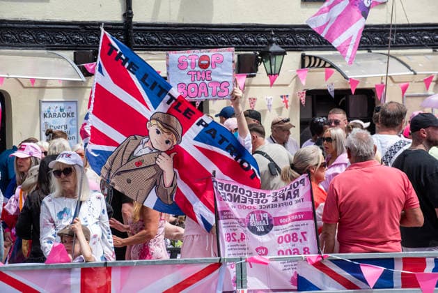 July 4, 2026, Dover, United Kingdom: Far-right protesters gather by the Golden Lion pub with flags and banners before a demonstration in Dover. Around 100-120 supporters of the Pink Ladies gathered from across the country in Dover, UK. The Pink Ladies is an anti immigration far-right movement. The far-right activists marched through central Dover to the Immigration Centre and they were confronted by a small group of antifascist counter-protesters during their march. Dover United Kingdom - ZUMAs197 20260704_aaa_s197_221 Copyright: xKrisztianxElekx