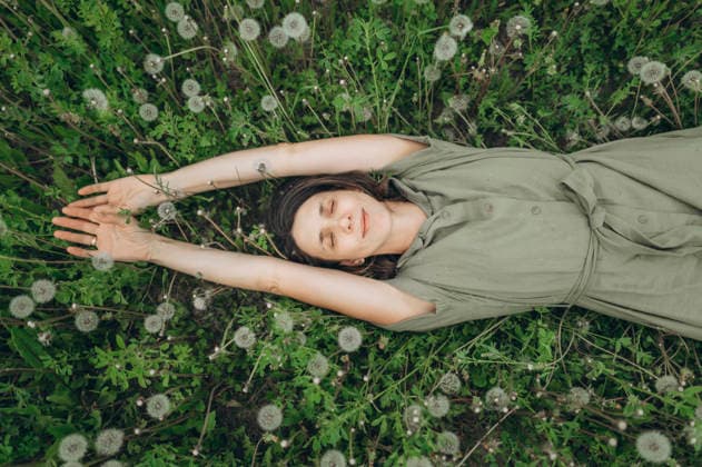 Woman relaxing alone in a green dandelion field model released, Symbolfoto, ANAF06108
