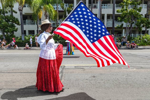 Coronado July 4th parade 2026, in California, USA - 04 Jul 2026 A woman waves a flag of the United States during the parade. Spectators line Orange Avenue as participants march through the annual Independence Day Parade in Coronado on July 4, 2026. The parade, featuring marching bands, military units, community organizations, and decorated vehicles, was part of the city s Independence Day celebrations marking America s 250th birthday and drew thousands of residents and visitors to the coastal community of San Diego area. Coronado United States Copyright: xMichaelxHoxWaixLeex xSOPAxImagesx Michael Ho_5977
