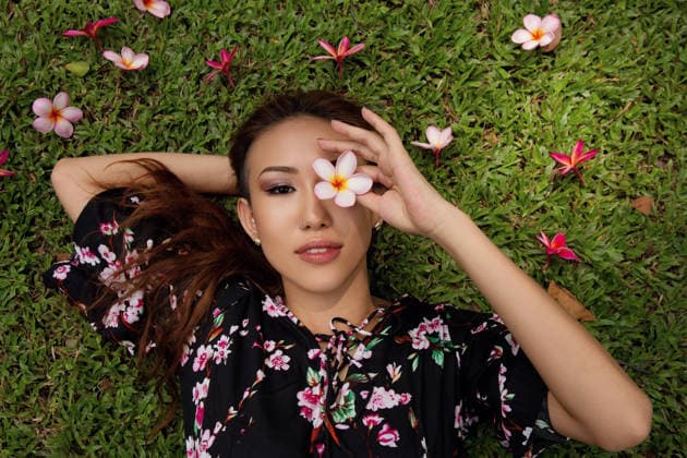 Model relaxing outdoors in a meadow holding a flower over the eye model released, Symbolfoto, EAF00443