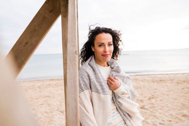 Smiling woman with scarf leaning on wooden structure at beach model released, Symbolfoto, JOSEF11021