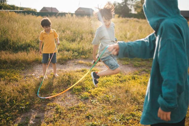 Boys play jump rope together in a sunny countryside yard model released, Symbolfoto, ANAF06275