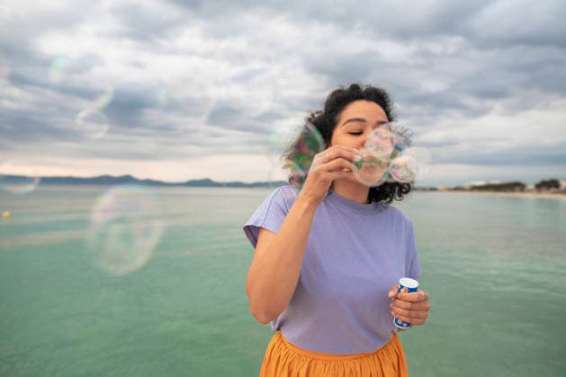 Woman having fun blowing bubbles in front of sea model released, Symbolfoto, JOSEF14813
