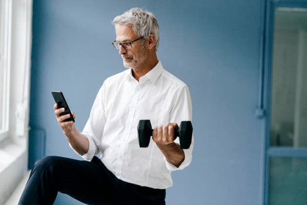 Successful manager using smartphone and training with a dumbbell model released, Symbolfoto property released, KNSF04876