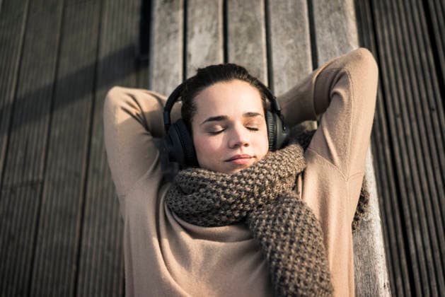 Portrait of woman listening music with cordless headphones relaxing on bench in autumn model released, Symbolfoto, MOEF01867