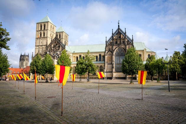 Große Prozession - Der Brauch des alljährliche Buß- und Bittgang reicht zurück bis ins Jahr 1382. 1382 starben in Münster mehr als 8000 Menschen an der Pest, Im Jahr darauf verwüstete ein Großbrand weite Stadtgebiete. Fahnen mit den Farben des Bistums auf dem Domplatz, St. Paulus Dom. Münster, Nordrhein-Westfalen, DEU, Deutschland, 05.07.2026 *** Grand Procession: The tradition of the annual penitential and supplicatory procession dates back to the year 1382. In 1382, more than 8,000 people died of the plague in Münster, The following year, a major fire ravaged large parts of the city. Flags bearing the colors of the diocese on Cathedral Square, St. Paul’s Cathedral, Münster, North Rhine-Westphalia, DEU, Germany, July 5, 2026