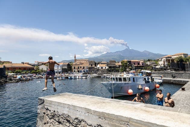 Mount Etna s Eruption As Seen From The Coast - Italy Mount Etna s eruption is seen from the coast in Pozzillo, Catania, Italy on July 5, 2026, as swimmers enjoy a dip in the sea at the small harbor with a cloud of smoke in the background. Photo by Francesco Enriquez IPA ABACAPRESS.COM Pozzillo Catania Italy  Copyright: xIPA ABACAx