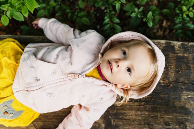 Little girl watches the sky while resting on a wooden bench outdoors model released, Symbolfoto, NDEF03368