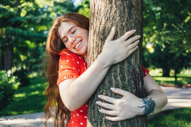 Happy young woman embracing tree with eyes closed in park model released, Symbolfoto property released, OYF00417