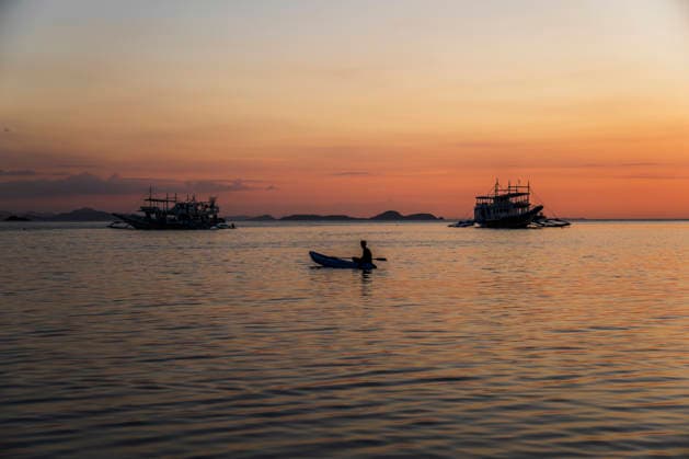 A male paddles a small boat during a tropical sunset in El Nido model released, Symbolfoto, PNAF07101