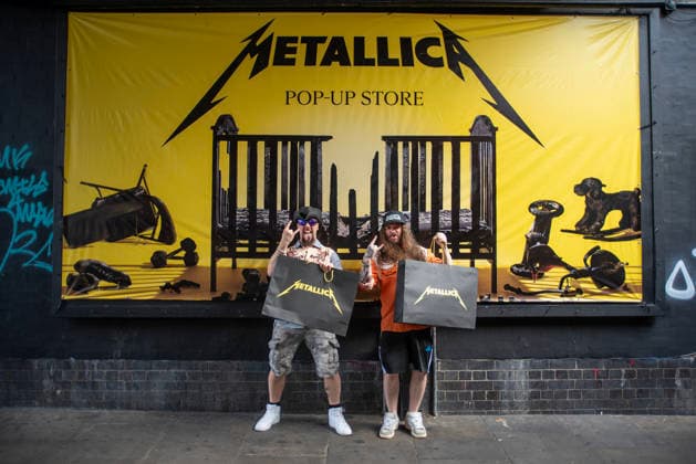 Metallica fans by the pop up ship in London, UK - 5Jul 2026 Two fans pose for a photo front of a Metallica banner outside the pop up shop in London. Metallica heavy metal band is having two concerts in London over the weekend as part of the M72 World Tour. Hundreds of Metallica fans were seen queuing up to buy some memorabilia by the Metallica pop up shop which is open for 4 days in London, UK. London United Kingdom Copyright: xKrisztianxElekx xSOPAxImagesx SSS_20260705_POPUP_SHOP_0011005015