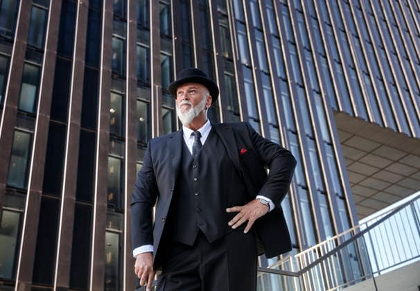Elegant businessman with bowler hat and walking cane, standing on stairs in the city model released, Symbolfoto, RHF02408