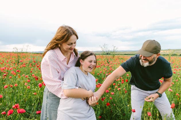 Happy mother and father play with their daughter in a poppy field model released, Symbolfoto, SIF01625