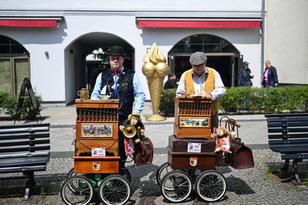 (260706) -- BERLIN, July 6, 2026 -- A barrel organ player (L) performs during the International Barrel Organ Festival 2026 in Berlin, Germany, July 5, 2026. The International Barrel Organ Festival 2026 was held in Berlin from July 3 to 5. Barrel organ players from across the world gathered here to entertain residents and visitors with a nostalgic musical celebration. ) GERMANY-BERLIN-BARREL ORGAN FESTIVAL ZhangxHaofu 