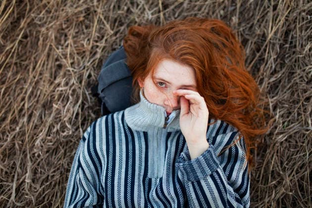 Portrait of teenage girl with red hair lying on dry grass in a sunny spring park model released, Symbolfoto, VCF01647