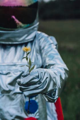 Spaceman holding flower, watching it grow model released, Symbolfoto, VPIF00593