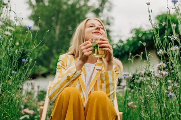 Woman drinks herbal tea in a blooming wildflower garden model released, Symbolfoto, VSNF05075