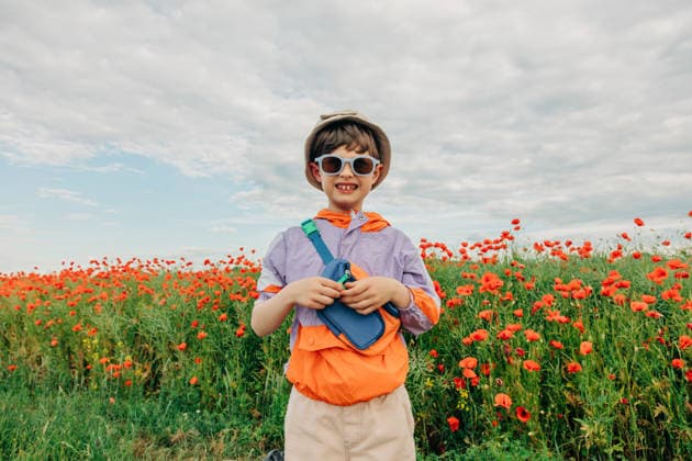 Smiling boy in retro tracksuit standing in a blooming poppy meadow model released, Symbolfoto, VSNF05139