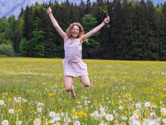 Jumping barefoot in a flower meadow in Mondsee Austria, WWF07201