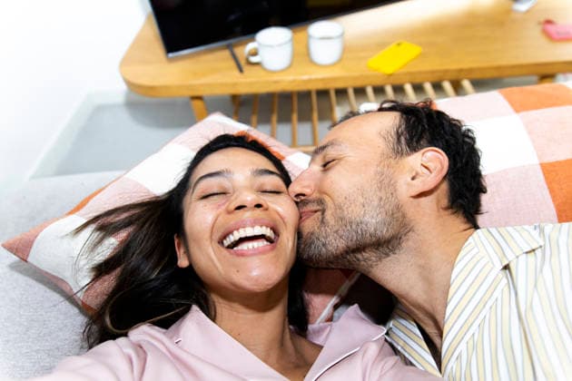 Cheerful man kisses laughing woman in pajamas taking selfie at home model released, Symbolfoto property released, YPF00331