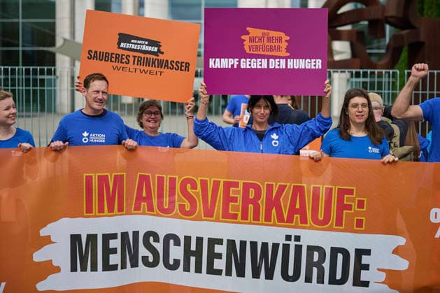 Ein Buendnis aus 15 Hilfsorganisationen protestiert am Montag (06.07.2026) vor dem Bundeskanzleramt in Berlin gegen Kuerzungen in der Entwicklungszusammenarbeit. Bei der Aktion Menschenwuerde im Ausverkauf fordern die Organisationen Aenderungen im Bundeshaushalt 2027. Dem Buendnis gehoeren unter anderem Brot fuer die Welt, misereor, Oxfam Deutschland sowie die Welthungerhilfe an. (Siehe epd-Meldung vom 06.07.2026) EDITORIAL USE ONLY *** A coalition of 15 aid organizations will protest on Monday, July 6, 2026, in front of the Federal Chancellery in Berlin against cuts to development cooperation. As part of the campaign Human Dignity on Sale, the organizations are calling for changes to the 2027 federal budget. The coalition includesinclu Copyright: epd-bild ChristianxDitsch epd-Protest_Kuerzungen2-kopieren