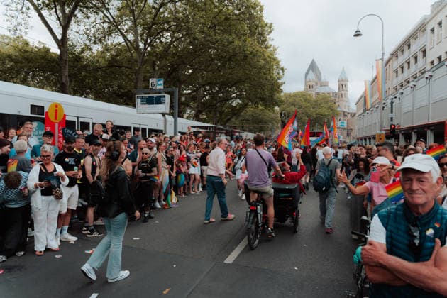 05.07.26, Cologne Pride 2026, parade and demonstration for diversity and equality A broad street scene at Neumarkt from Cologne Pride 2026 shows spectators and participants lining the parade route, with rainbow flags, parade groups and a church tower visible in the distance. Cologne Cologne NRW Germany