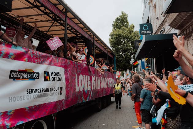 05.07.26, Cologne Pride 2026, parade and demonstration for diversity and equality A Cologne Pride float by Cologne Pride, House of Love and Serviceplan Group passes through the city, with people on the float waving fans and signs to the crowd. Cologne Cologne NRW Germany