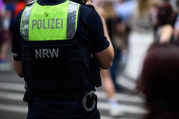 COLOGNE, GERMANY - 5 JULY, 2026: Police officer in a high-visibility vest stands on duty during a crowded Pride parade.  Copyright: xx